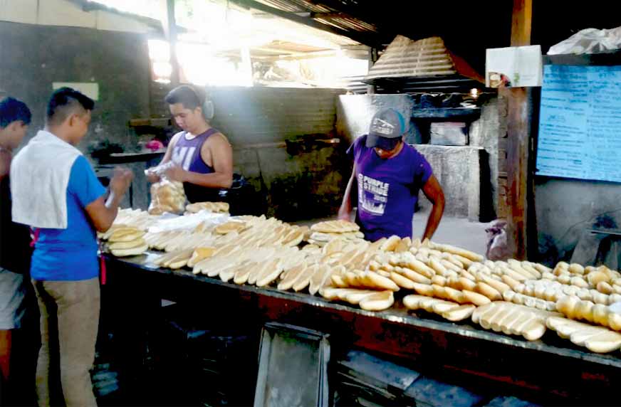 Cuatro panaderos empacando el pan recien salido del horno